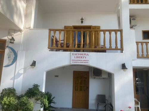 a white building with a balcony and a door at Liberty-Studio Ν5 in Georgioupolis