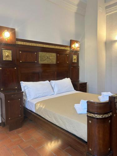 a bedroom with a large bed with a wooden headboard at Albergo Palazzo Costa in Beverino