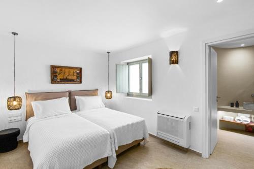 a white bedroom with a bed and a mirror at Asana 1 in Márpissa