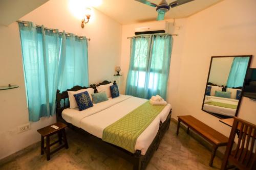 a bedroom with a bed with blue curtains and a mirror at Le Clarisse Guest House in Puducherry