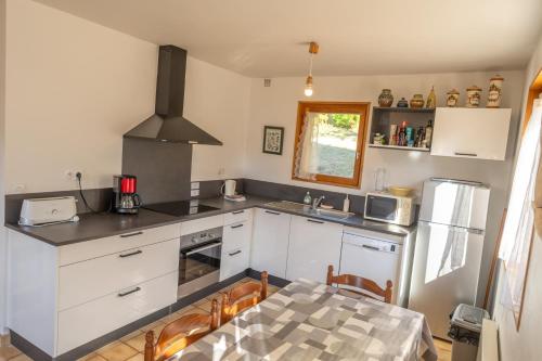 a kitchen with white cabinets and a table with chairs at Chalet Les écrins Guillestre Vars Risoul Queyras in Guillestre