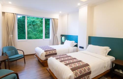 a hotel room with two beds and a chair at Bhutan Peaceful Residency and Spa in Thimphu