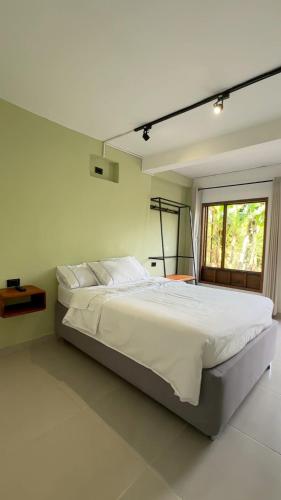 a bedroom with a large white bed with a window at Hotel Boutique Albania in Otanche