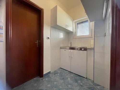 a small kitchen with a sink and a door at Apartmani Baki in Podstrana