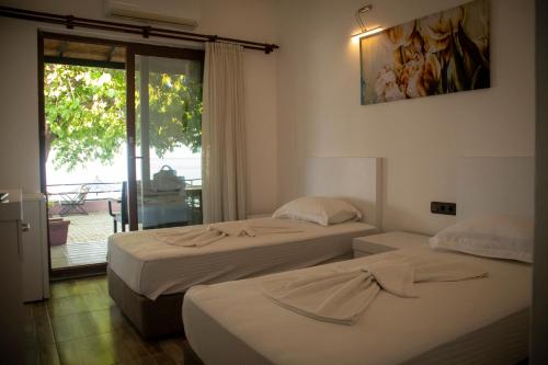 two beds in a room with a balcony at THE SANDHİLl OTEL RESTAURANT in Kemer