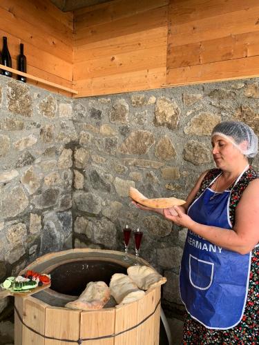 a woman holding a piece of bread in front of a barrel at White House In Borjomi in Borjomi