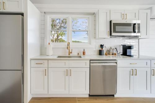 a white kitchen with white cabinets and a sink at Dockside 2BR - Marina - Dining - Charter Access Unit A in Montauk