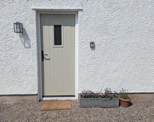 a door in a white building with two potted plants at Field Edge Barn in Silverdale