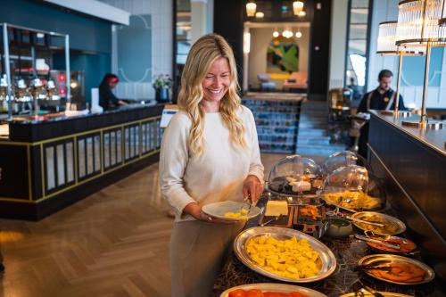 a woman holding a plate of food at a buffet at Hotel Mürren Palace in Mürren