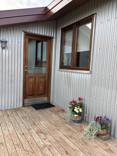 a house with a wooden door and flowers on a deck at Farmhouse on the Golden Circle in Selfoss