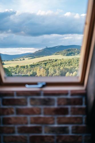 a window view of a field from a brick wall at Penzion Na Červeném Potoce in Králíky