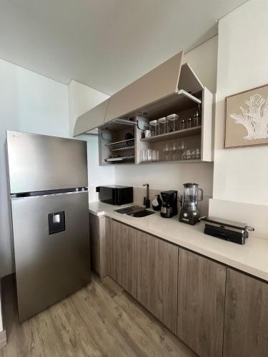 a kitchen with a stainless steel refrigerator and wooden cabinets at Almare Apartamentos nuevos in Gustavo Rojas Pinilla International