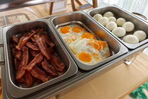 un vassoio con prodotti per la colazione, uova e pancetta di Villa Ferrara Royal Resort & Spa a Coriano