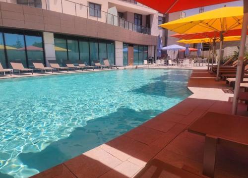 a swimming pool with chairs and umbrellas in a building at Mercury Gardens in St Julian's
