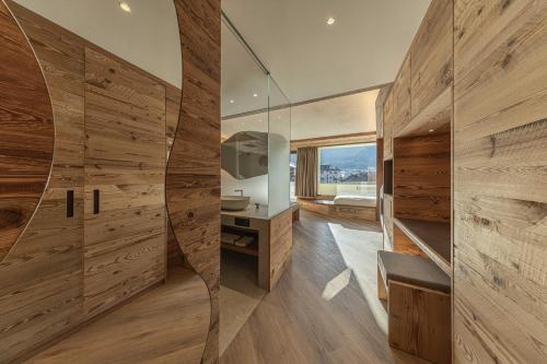 a bathroom with wood paneling and a glass wall at Hotel Mirabello - Slow Hotel Benessere in Fiera di Primiero
