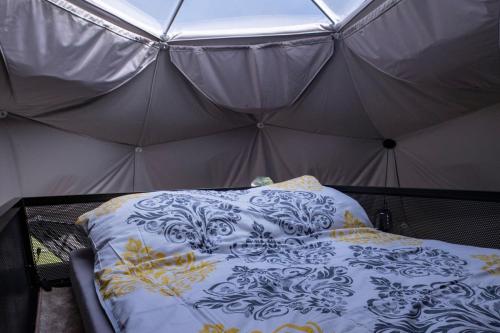 a bed in a tent with a white and yellow blanket at Tatra Glamp Okrzeszyn - Siec noclegowa Tatra Glamp in Okrzeszyn