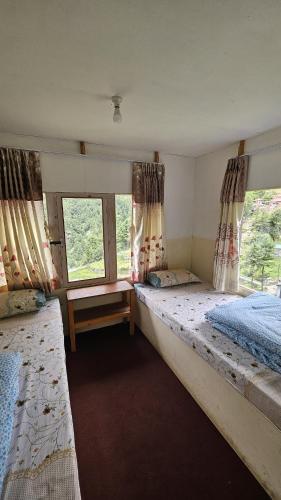 a bedroom with two beds and a window at Buddha Lodge and Restaurant, Monjo in Khumjung