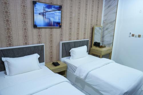 a room with two beds and a tv on the wall at hotel rose garden فندق روز جاردن in Duqm