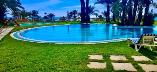 a large swimming pool with a bench in the grass at Wonderful Hotel Apartment in Hammamet