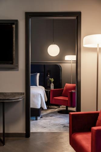 a bedroom with a bed and a red chair and a mirror at The Marmorosch Bucharest, Autograph Collection in Bucharest
