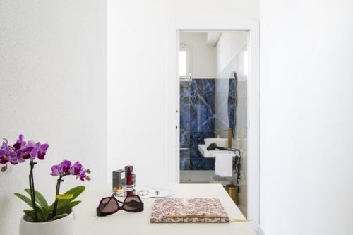 a bathroom with a vase of purple flowers on a counter at EnSe Affittacamere in Tortolì