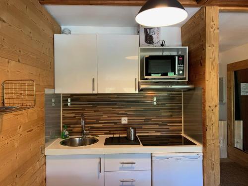 une cuisine avec un évier et un micro-ondes dans l'établissement Charmant 2 pièces pour 5 pers, au pied des pistes, 24m², Vieil Alpe, Alpe d'Huez - FR-1-405-217, à Huez
