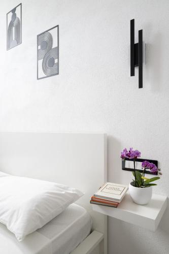 a white bedroom with a bed and a table with flowers at EnSe Affittacamere in Tortolì
