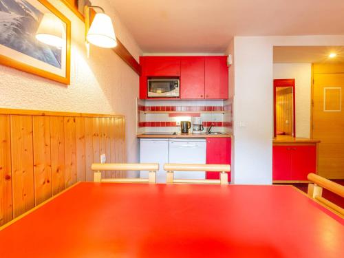 une cuisine avec des placards rouges et une grande table en bois dans l'établissement Appartement 34m² Plagne 1800 avec Parking et Animaux acceptés - FR-1-351-248, à La Plagne Tarentaise