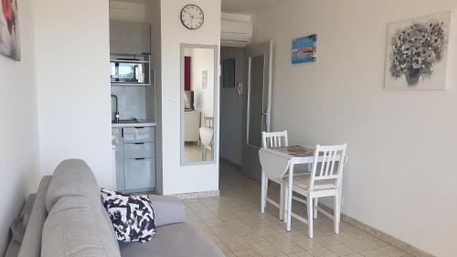 un salon avec un canapé, une table et des chaises dans l'établissement Lumineux studio à Bandol, 2 pers, face à la plage, à Bandol
