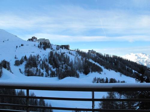 Une montagne enneigée avec un bâtiment en haut dans l'établissement Appartement moderne à Plagne Centre avec balcon, 2 chambres et Wifi - FR-1-351-93, à La Plagne