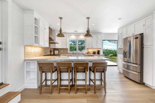 a kitchen with white cabinets and a stainless steel refrigerator at Dockside 2BR - Prime Location on the Marina Unit B in Montauk