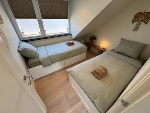 a attic bedroom with two beds and a window at Nieuw in 2025 Bundi Coast Vakantiehuis bij Strand & Duinen in Egmond aan Zee