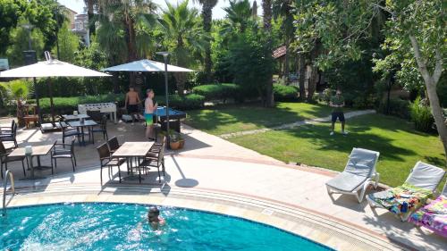 a pool with chairs and tables and people in a yard at LEMAS SUITE HOTEL in Side