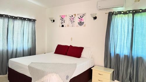 a bedroom with a bed with red pillows and curtains at Golden Sunset House in Acajutla