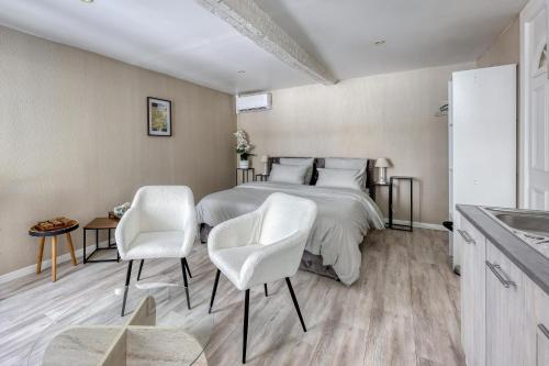 a bedroom with a bed and two white chairs at Studio N1 Draguignan Centre in Draguignan