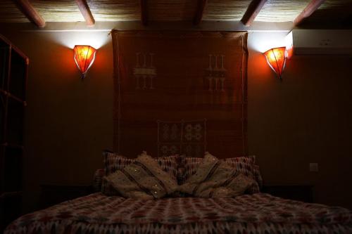 a bedroom with a bed with two lights on the wall at Villa Zazate in Ouarzazate