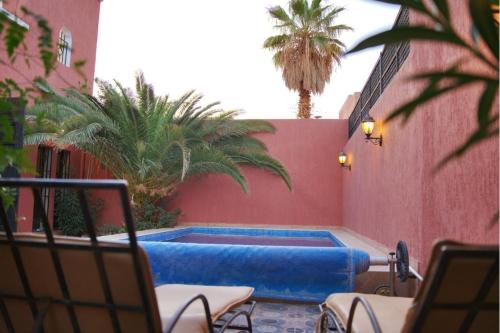 a swimming pool in a courtyard with palm trees at Villa Zazate in Ouarzazate