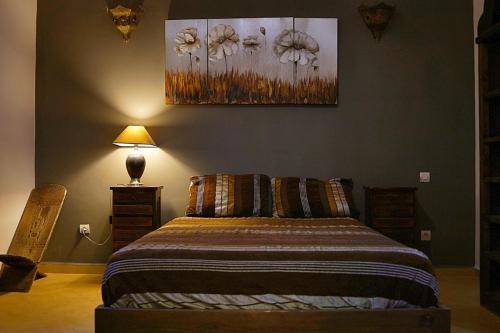a bedroom with a bed and a painting on the wall at Villa Zazate in Ouarzazate
