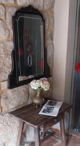 a table with a mirror and a vase with flowers on it at Hotel Gastronómico Casa Rosalia in Brion