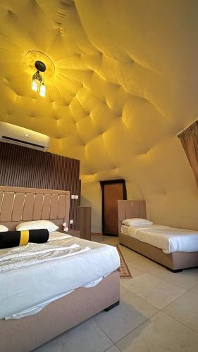 two beds in a room with a yellow ceiling at environment wadi rum in Wadi Rum