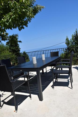 a black table and chairs with the ocean in the background at Dendrokipos in Mouresi