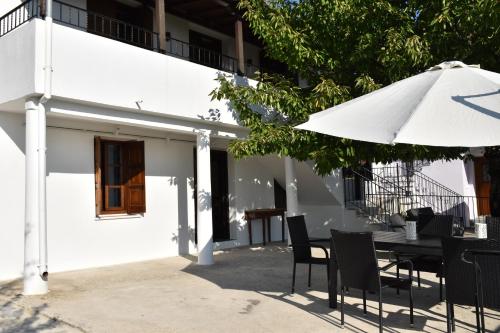 a table and chairs with an umbrella in front of a building at Dendrokipos in Mouresi