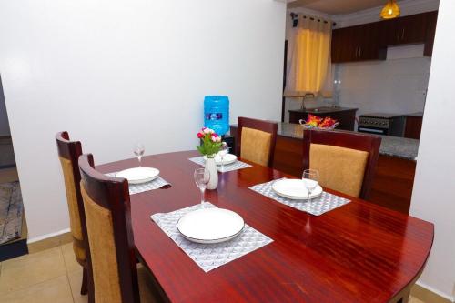 a dining room table with plates and wine glasses at Modern 3BR Apartment near JKIA and SGR with Free Parking in Athi River