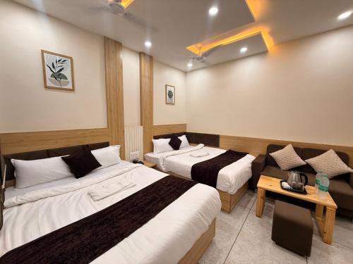 a hotel room with two beds and a couch at Hotel Kusum Kunj in Ujjain