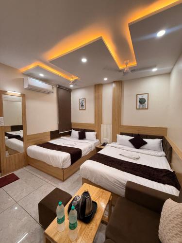 a hotel room with two beds and a couch at Hotel Kusum Kunj in Ujjain