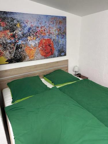 a bedroom with a green bed with a painting on the wall at Haus Heiken Apartment Sonnenblume in Altenburg