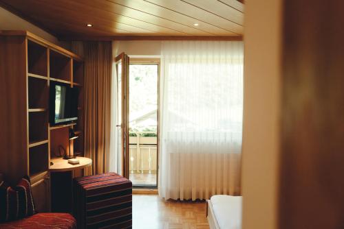 a hotel room with a bed and a sliding glass door at Pension Rudolph in Gaschurn