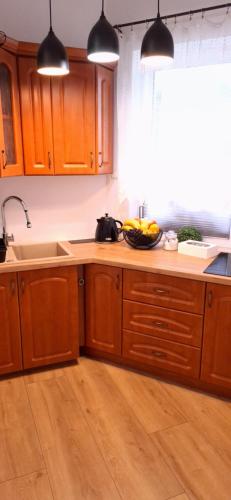 a kitchen with wooden cabinets and a bowl of fruit on the counter at Kaprys Apartament in Brenna
