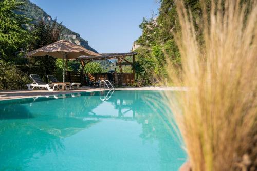 a swimming pool with an umbrella and some chairs at Château De La Caze Piscine & Spa - Ste Enimie in Sainte-Énimie