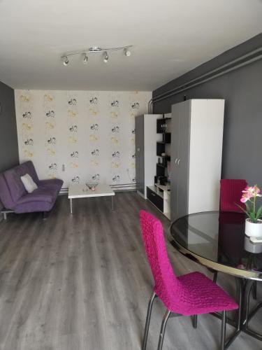 a living room with a glass table and purple chairs at Apartman M&D in Pančevo